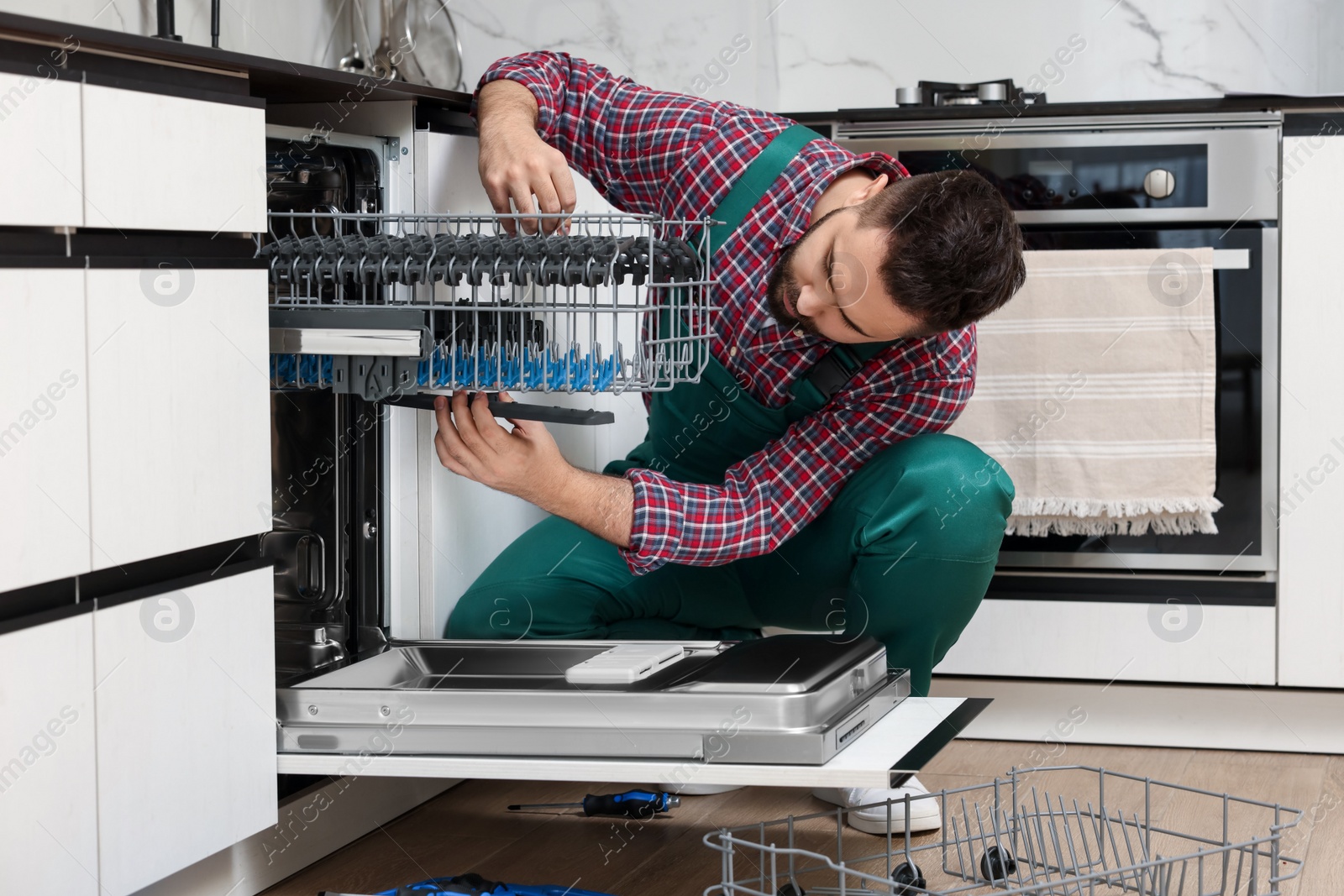 Photo of Serviceman repairing dishwasher cutlery rack in kitchen