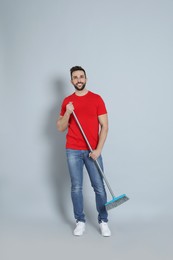 Photo of Handsome man with broom on grey background
