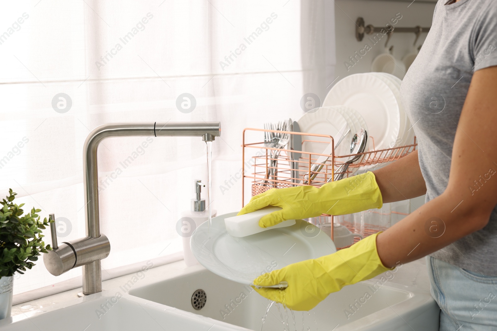 Photo of Woman washing plate at sink in kitchen, closeup