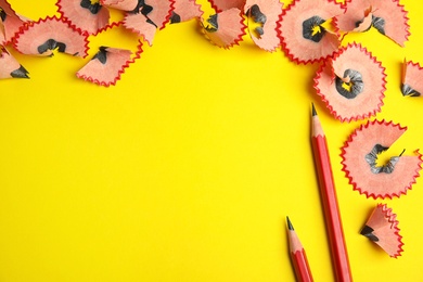 Photo of Pencils and shavings on yellow background, flat lay. Space for text