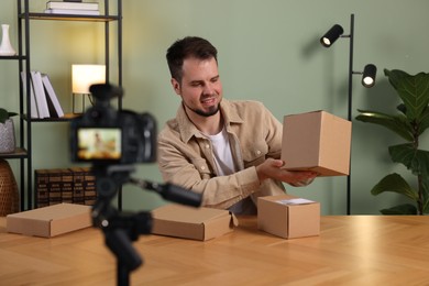 Smiling blogger with many parcels recording video at home