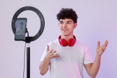 Photo of Smiling teenage blogger explaining something while streaming on white background