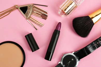 Flat lay composition with bright lipstick and accessories on pink background