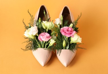 Stylish women's high heeled shoes with beautiful flowers on pale orange background