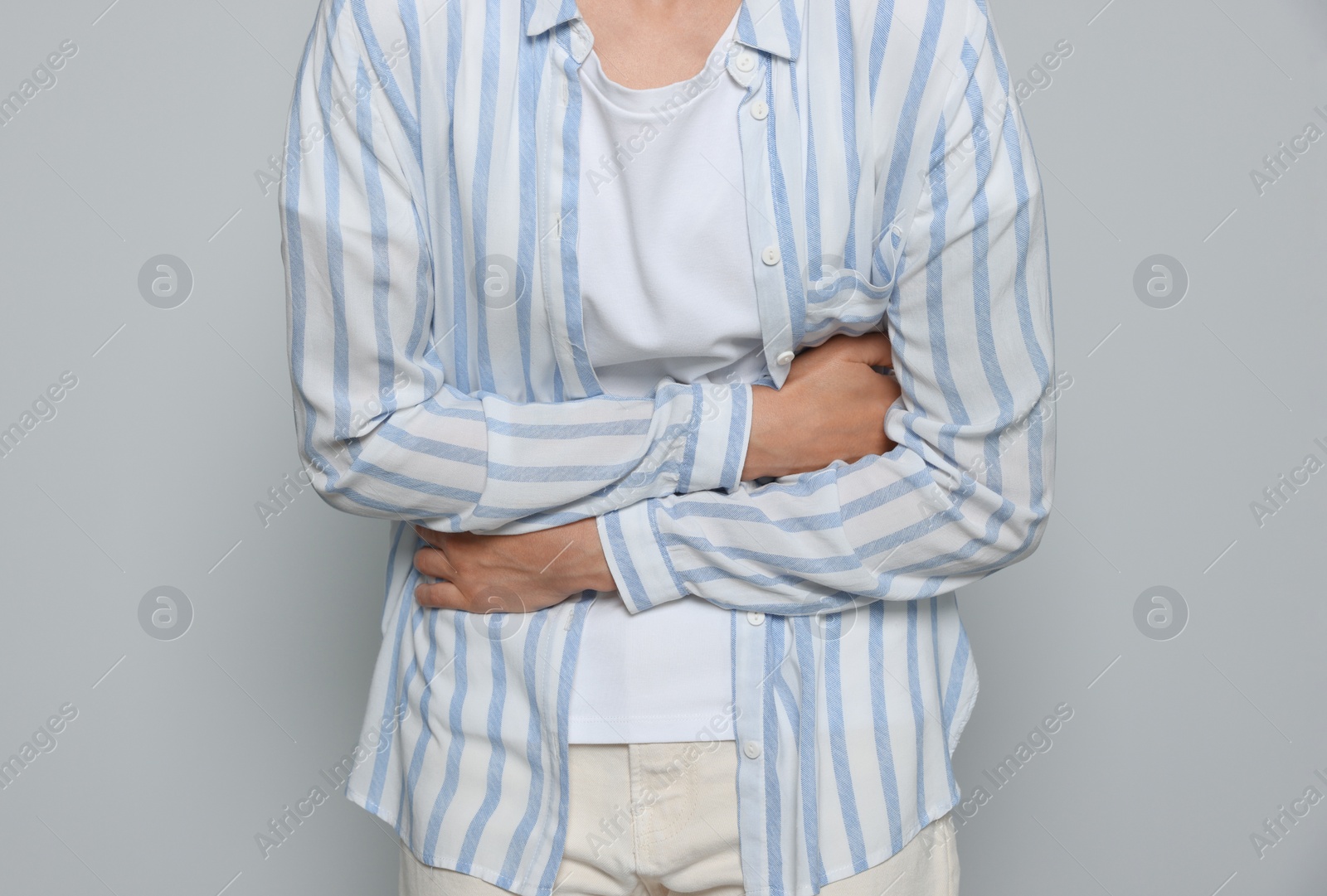 Photo of Young woman suffering from menstrual pain on light grey background, closeup