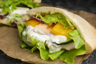 Photo of Delicious pita sandwich with chicken breast and vegetables on parchment paper, closeup