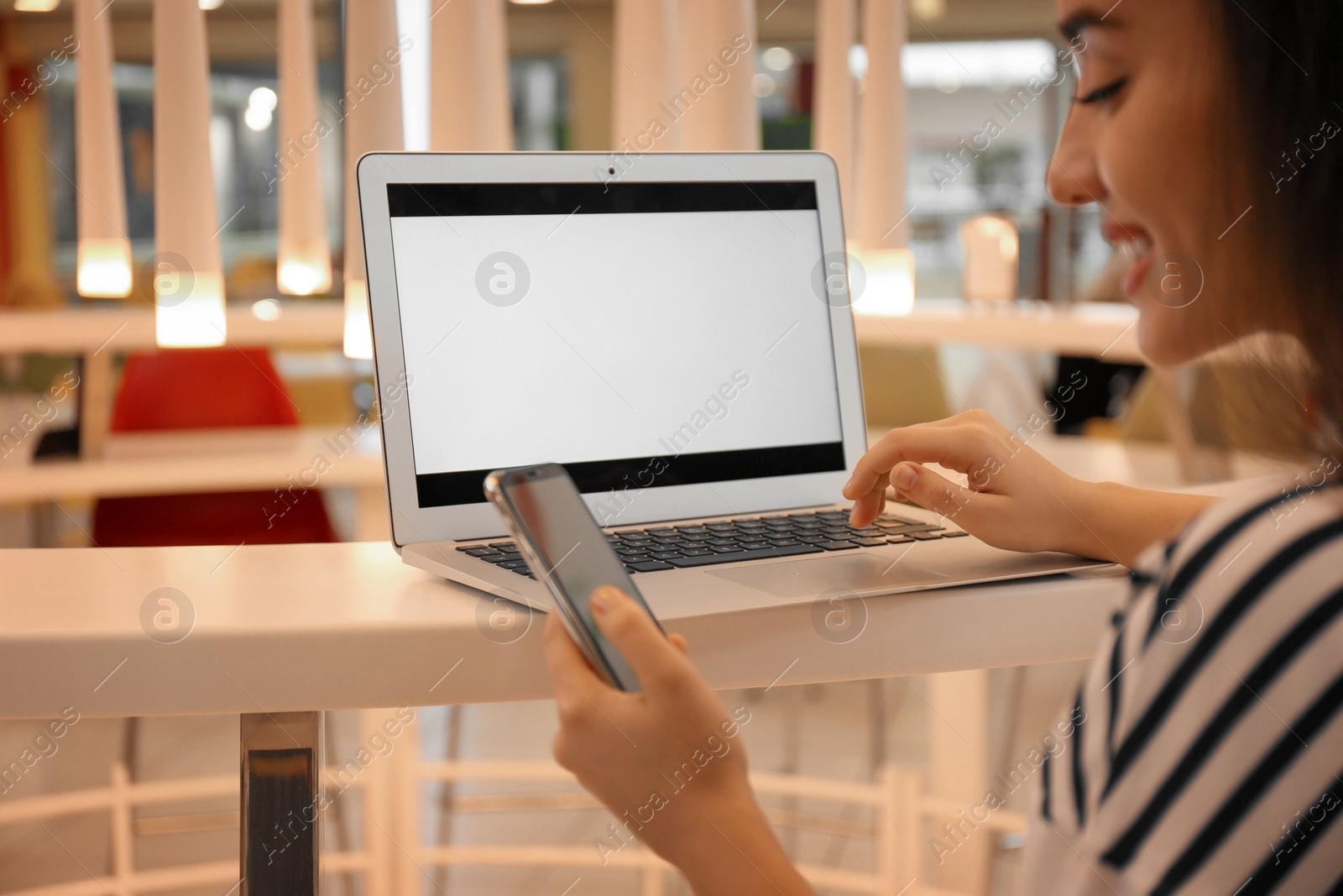 Photo of Blogger with laptop and mobile phone in cafe, closeup