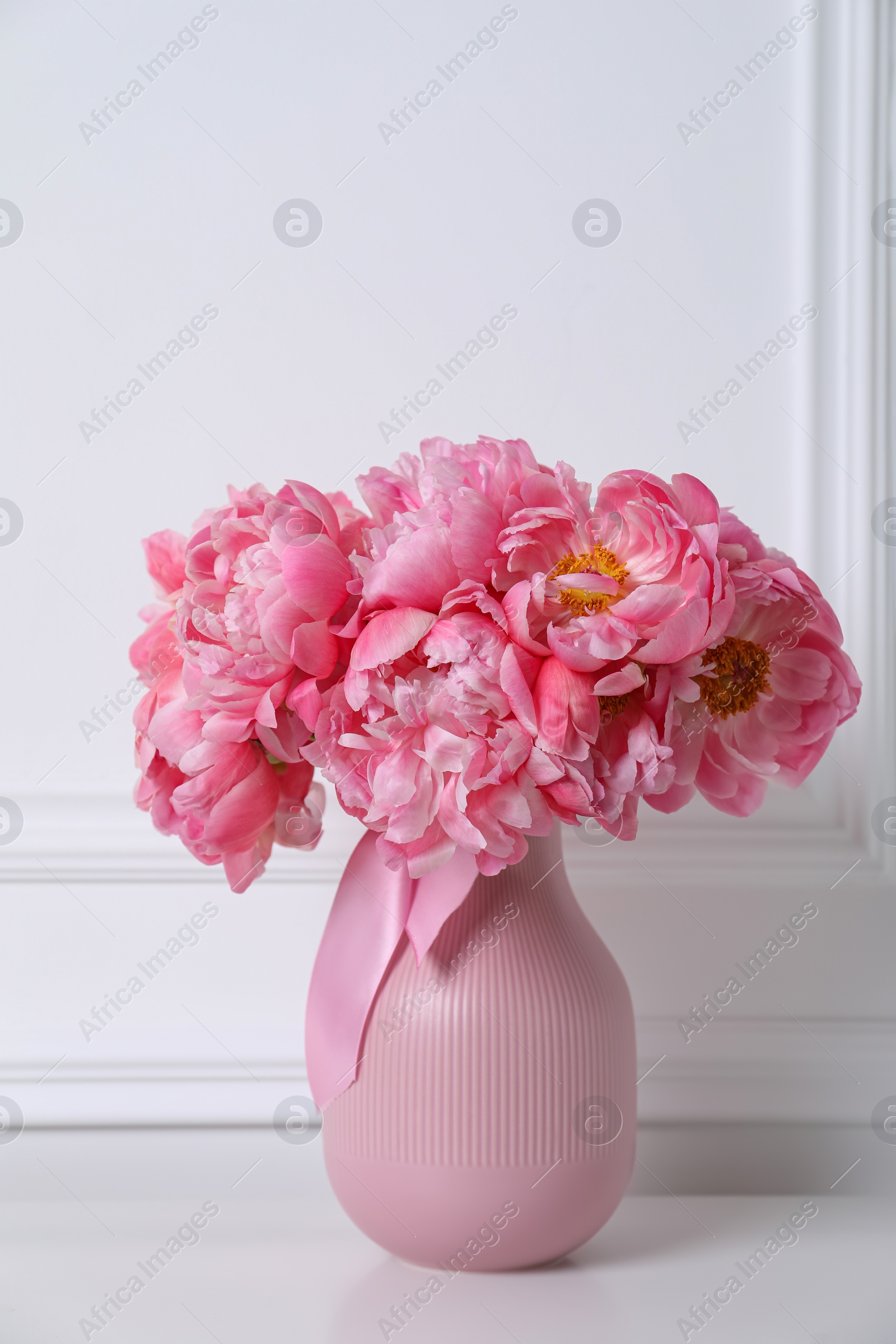 Photo of Beautiful bouquet of pink peonies in vase near white wall