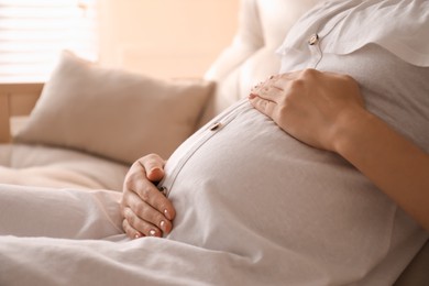 Photo of Pregnant young woman touching belly at home, closeup