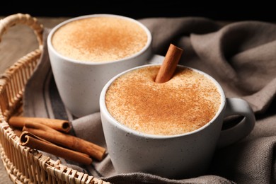 Photo of Delicious eggnog with cinnamon on wooden table, closeup