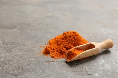 Photo of Scoop and powdered red pepper on table, space for text. Aromatic spice