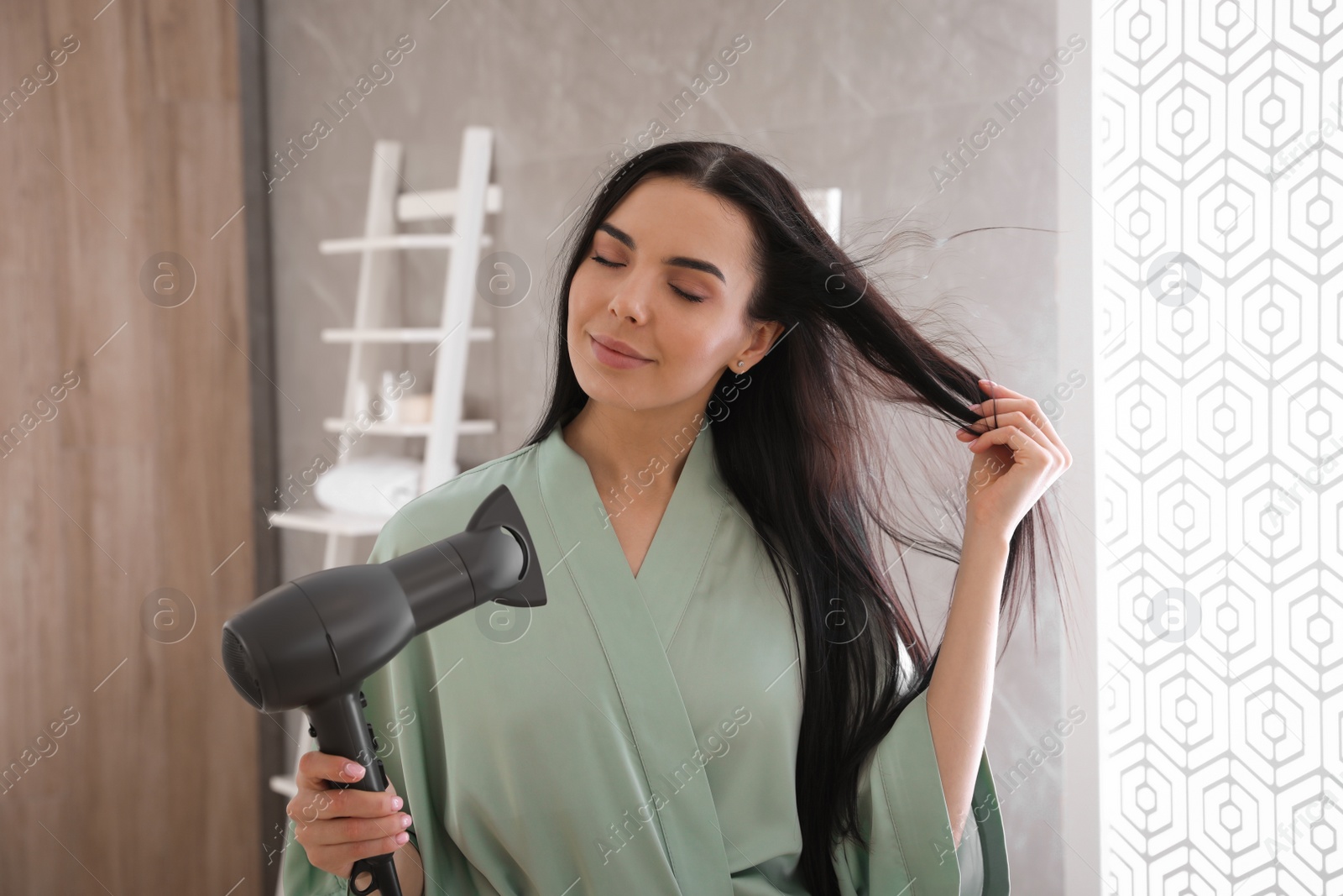 Photo of Beautiful young woman using hair dryer in bathroom