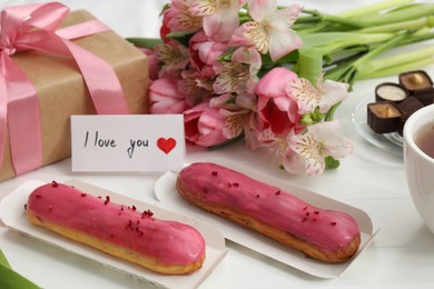 Photo of Tasty breakfast served in bed. Delicious desserts, flowers, gift box and card with phrase I Love You on tray, closeup