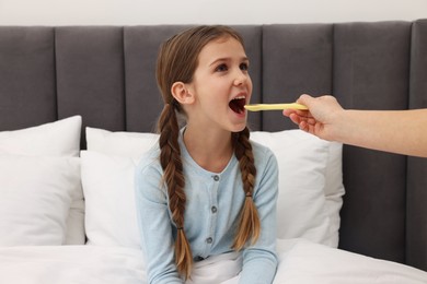 Mother giving cough syrup to her daughter at home