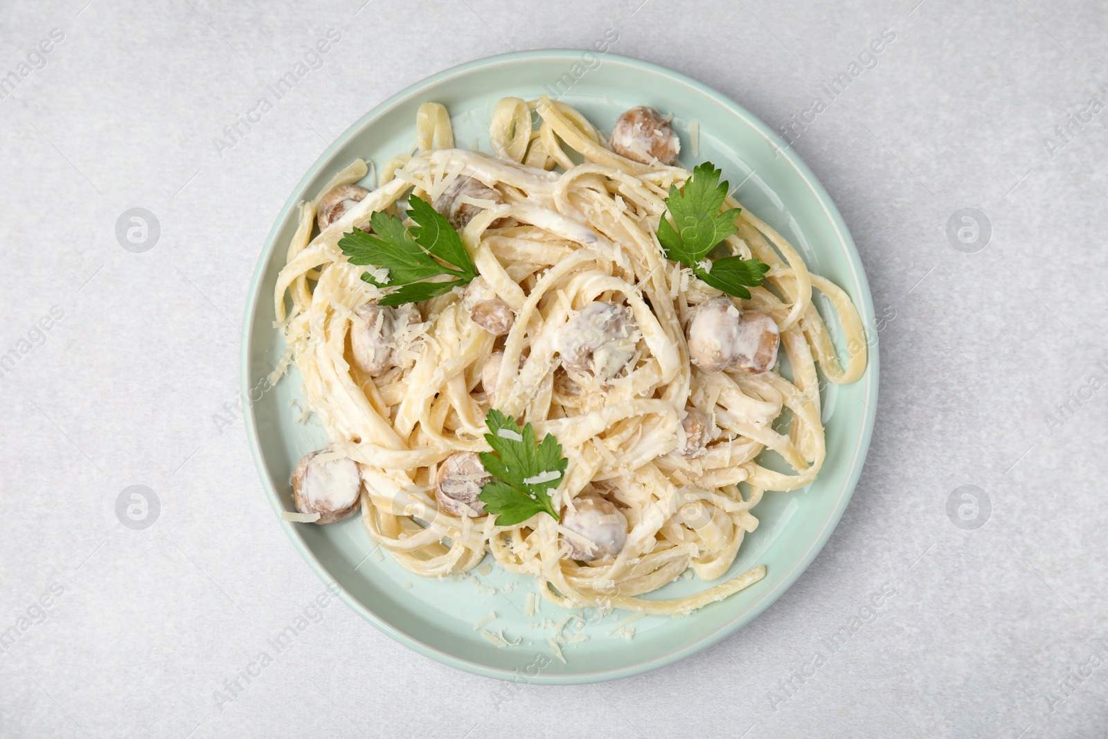 Photo of Delicious pasta with mushrooms on light grey table, top view