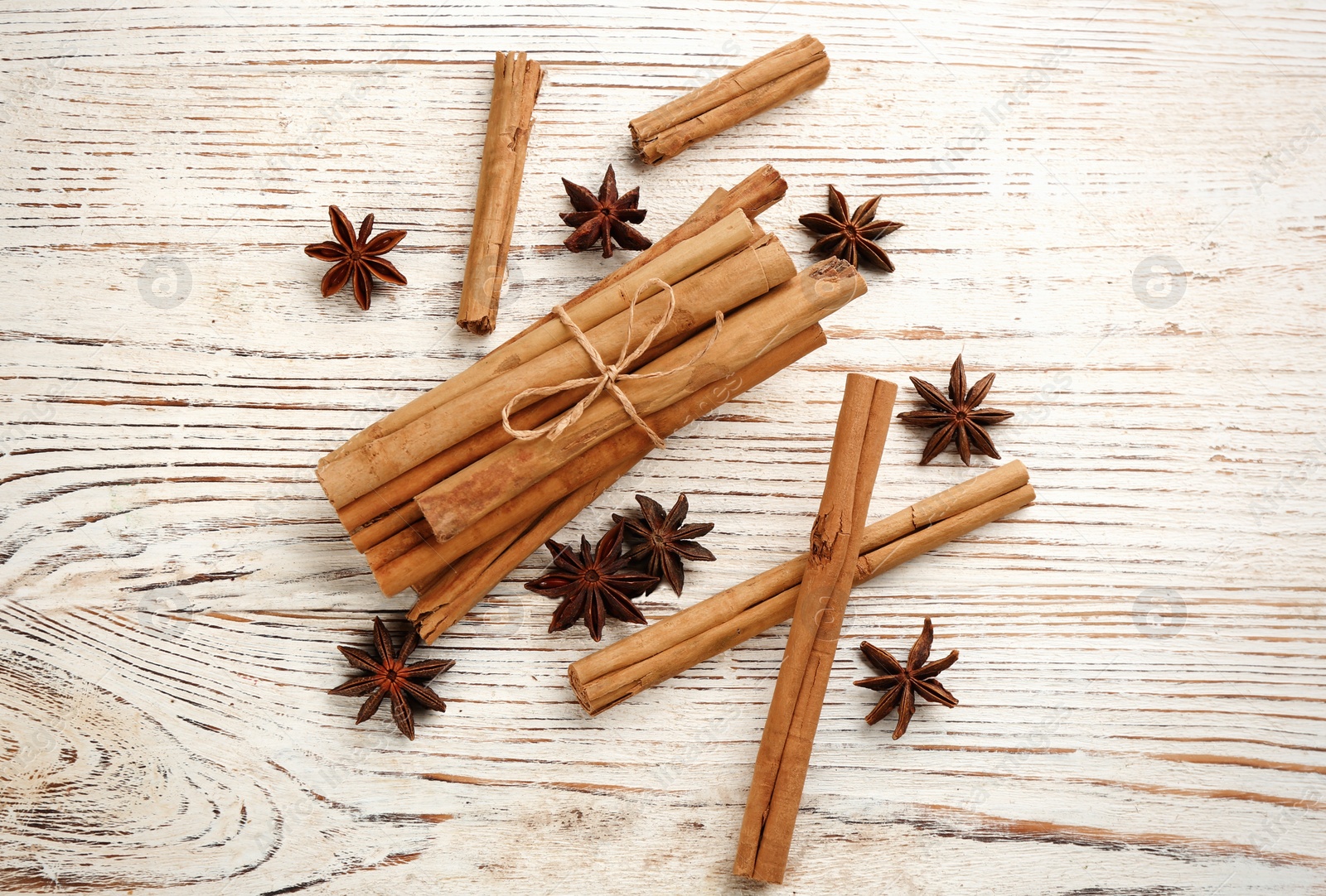 Photo of Aromatic cinnamon sticks and anise on white wooden table, flat lay