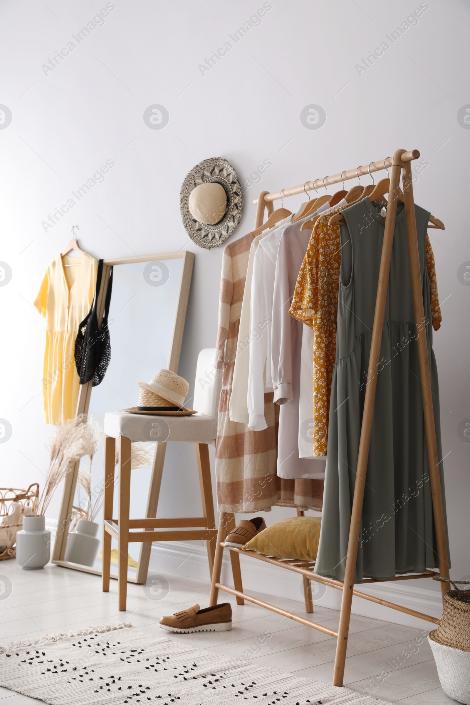 Photo of Rack with stylish women's clothes and mirror indoors. Interior design