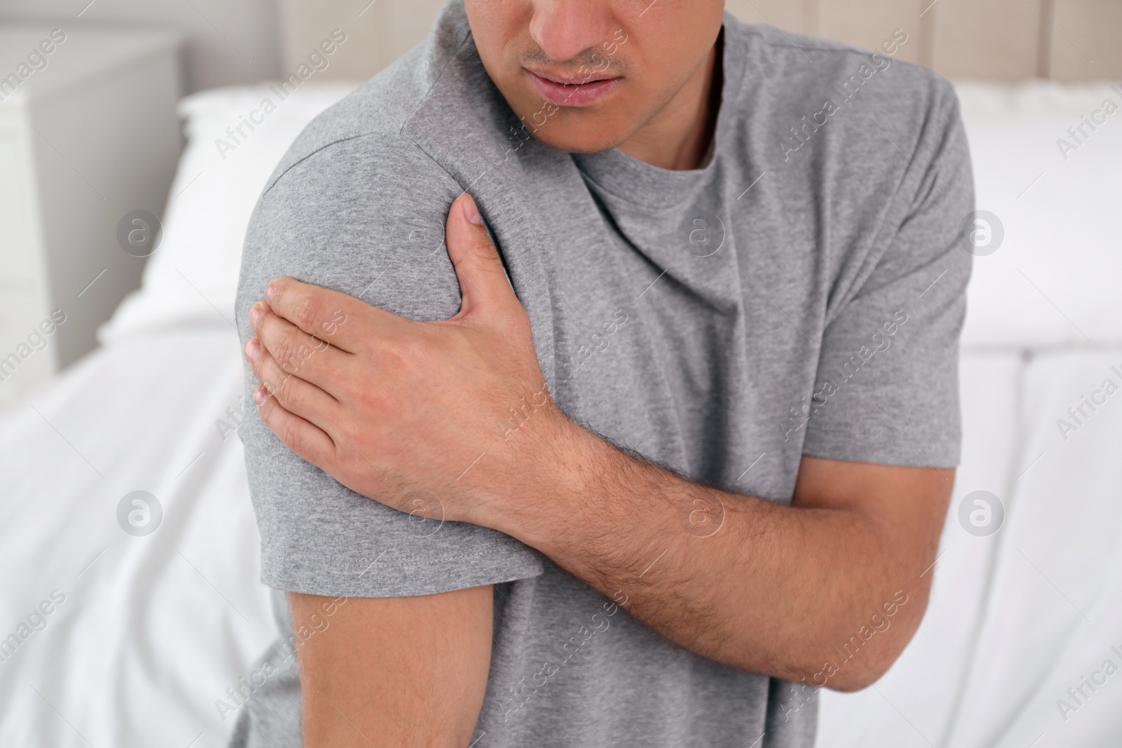 Photo of Man suffering from shoulder pain at home, closeup