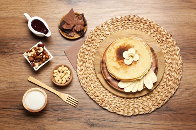 Photo of Delicious crepes with different products on wooden table, flat lay
