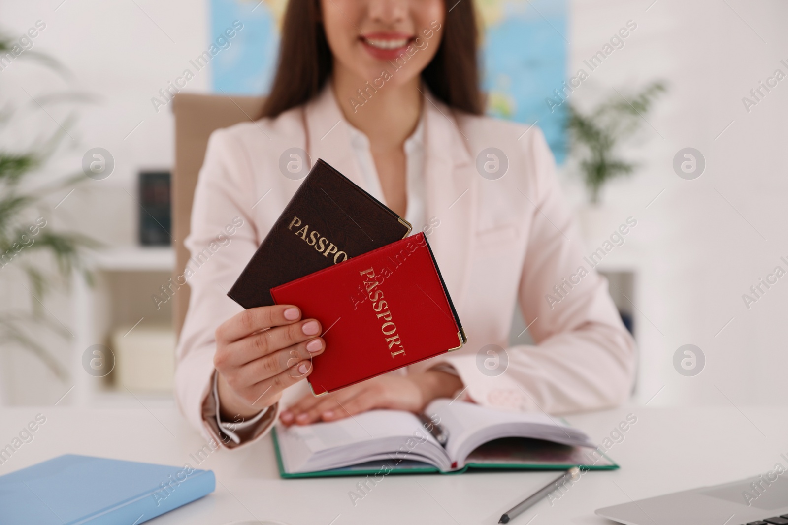 Photo of Happy manager holding passports at desk in travel agency, closeup