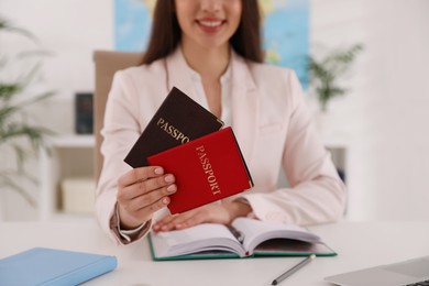 Photo of Happy manager holding passports at desk in travel agency, closeup