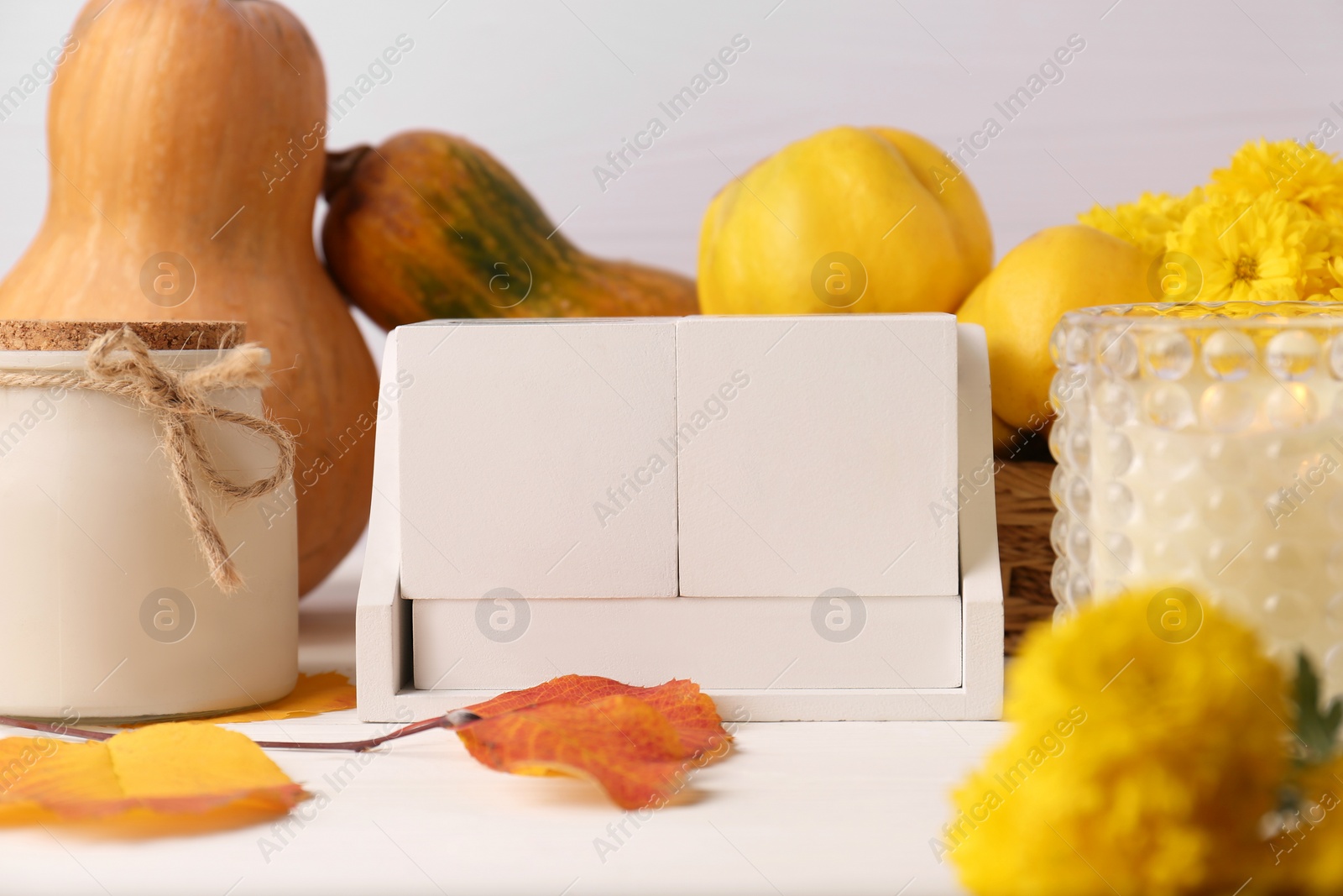 Photo of Thanksgiving day, holiday celebrated every fourth Thursday in November. Block calendar, candle, pumpkins, quinces and chrysanthemum flowers on white wooden table