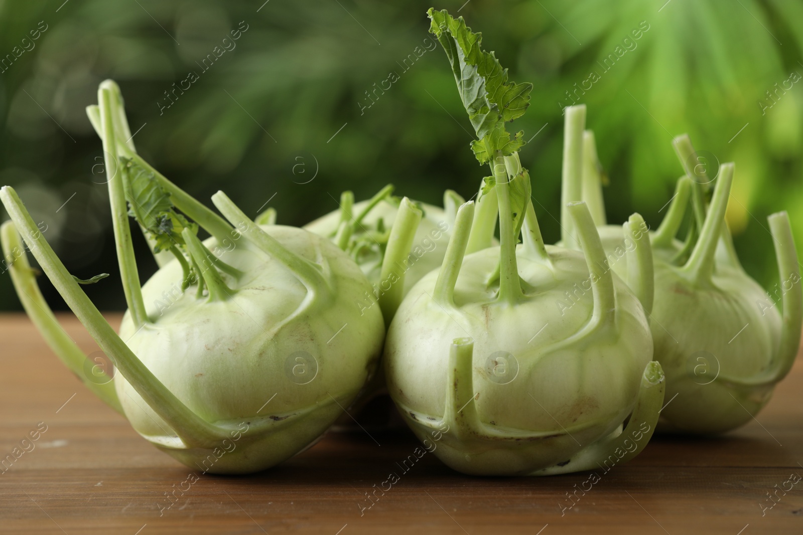 Photo of Whole ripe kohlrabi plants on wooden table, closeup