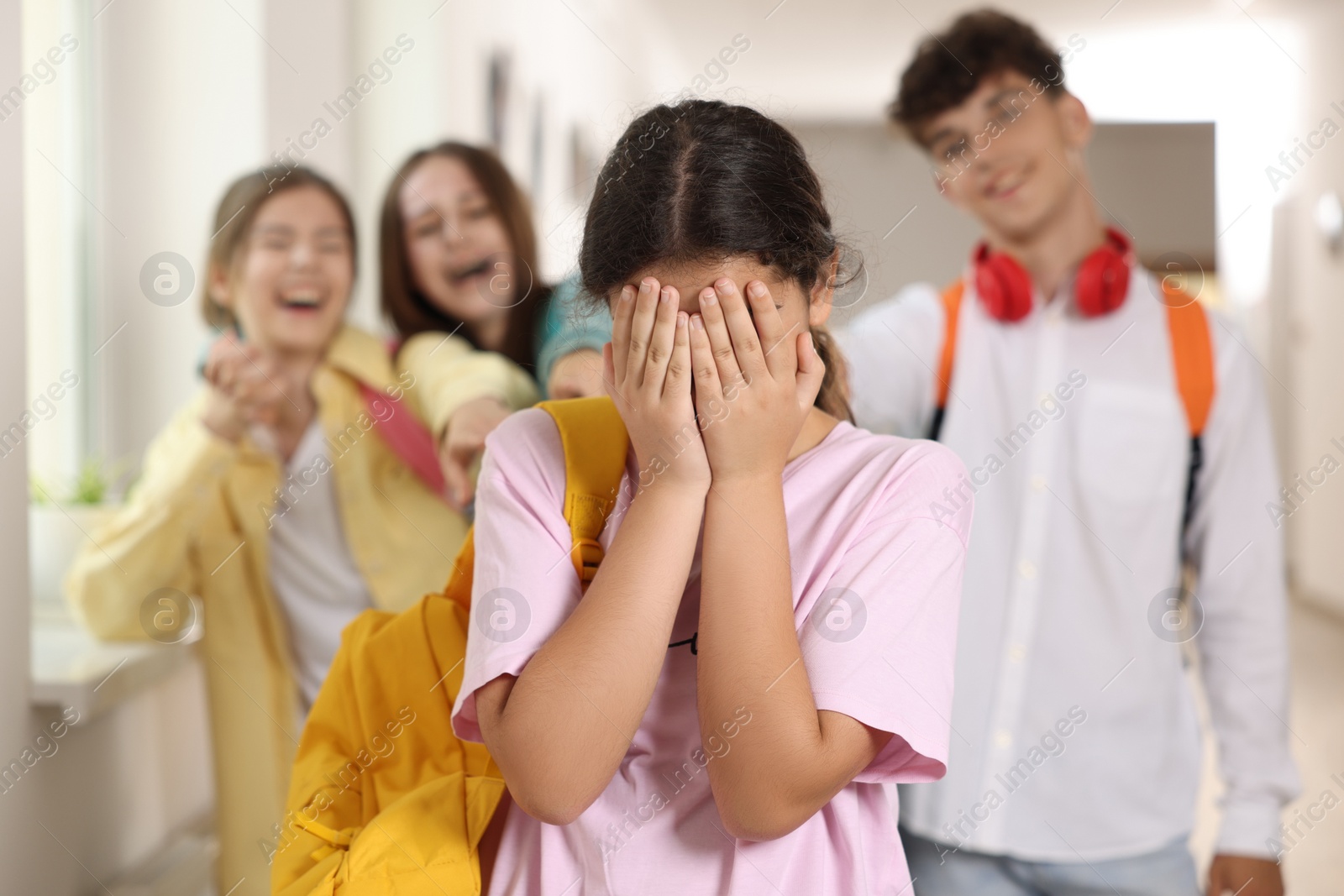 Photo of Teen problems. Lonely girl standing separately from other students at school