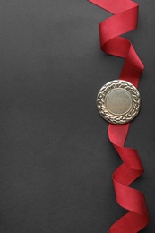 Gold medal on black background, top view with space for text. Symbol of victory