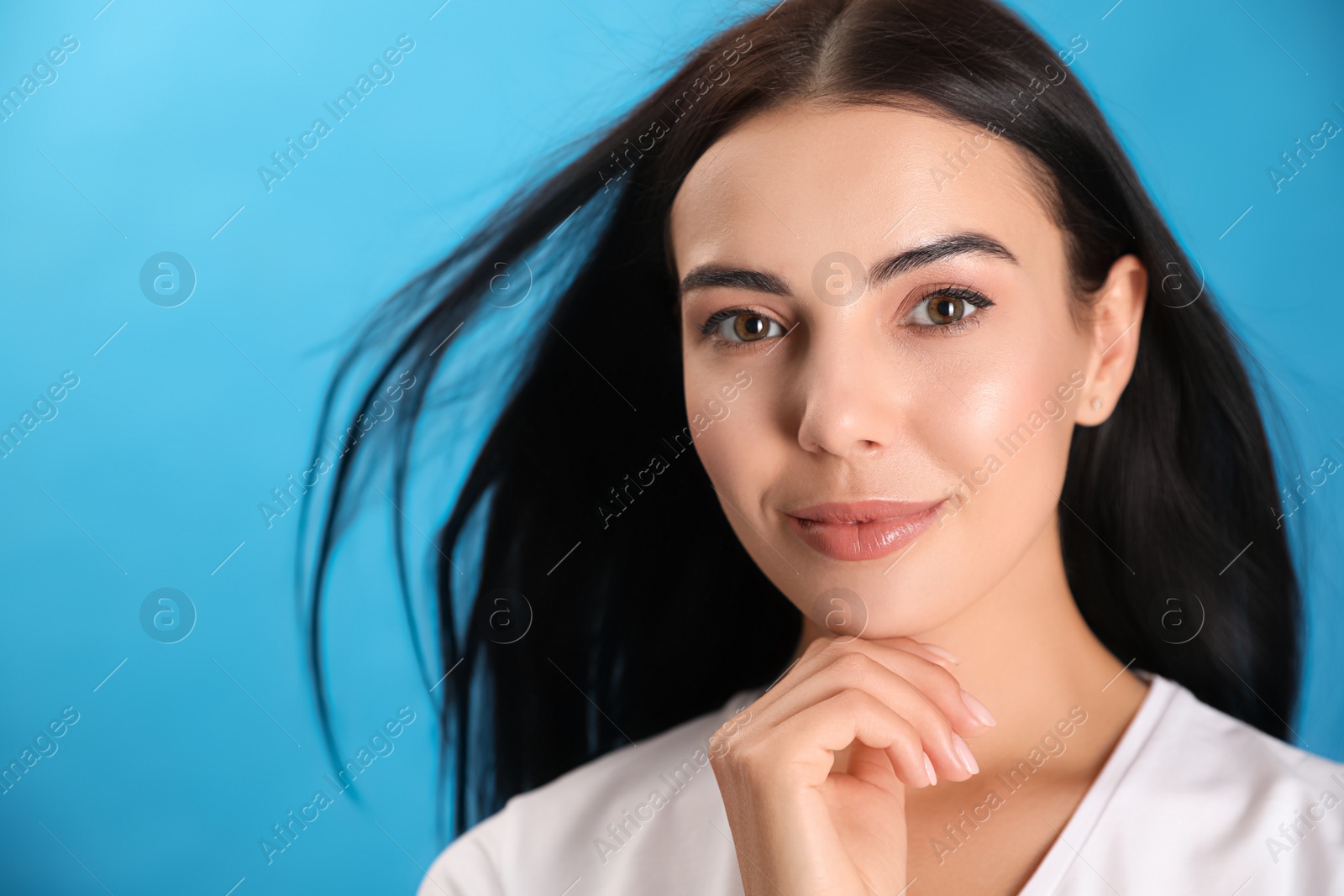 Photo of Portrait of beautiful young woman on light blue background, closeup