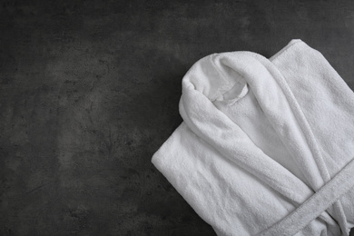 Photo of Clean folded bathrobe on black stone background, top view. Space for text