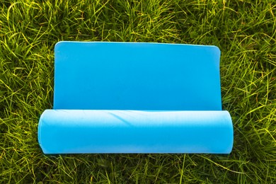 Photo of Blue karemat or fitness mat on fresh green grass outdoors, top view