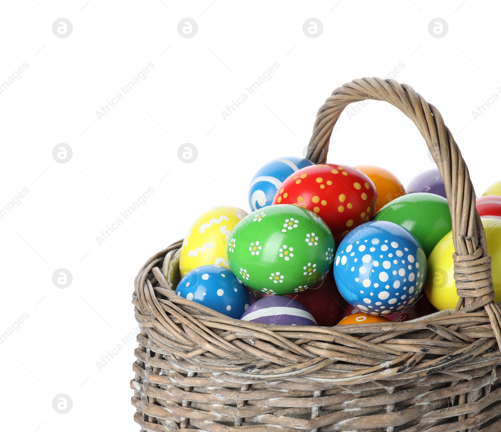 Photo of Decorated Easter eggs in wicker basket on white background