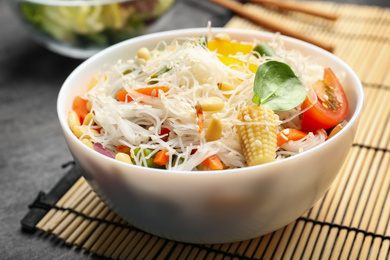 Photo of Tasty cooked rice noodles with vegetables on grey table