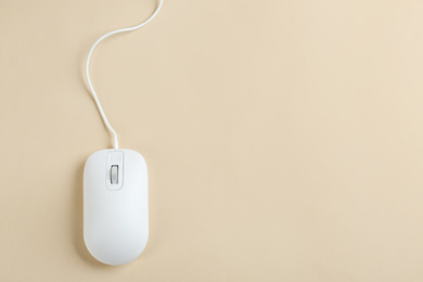 Modern wired optical mouse on beige background, top view. Space for text