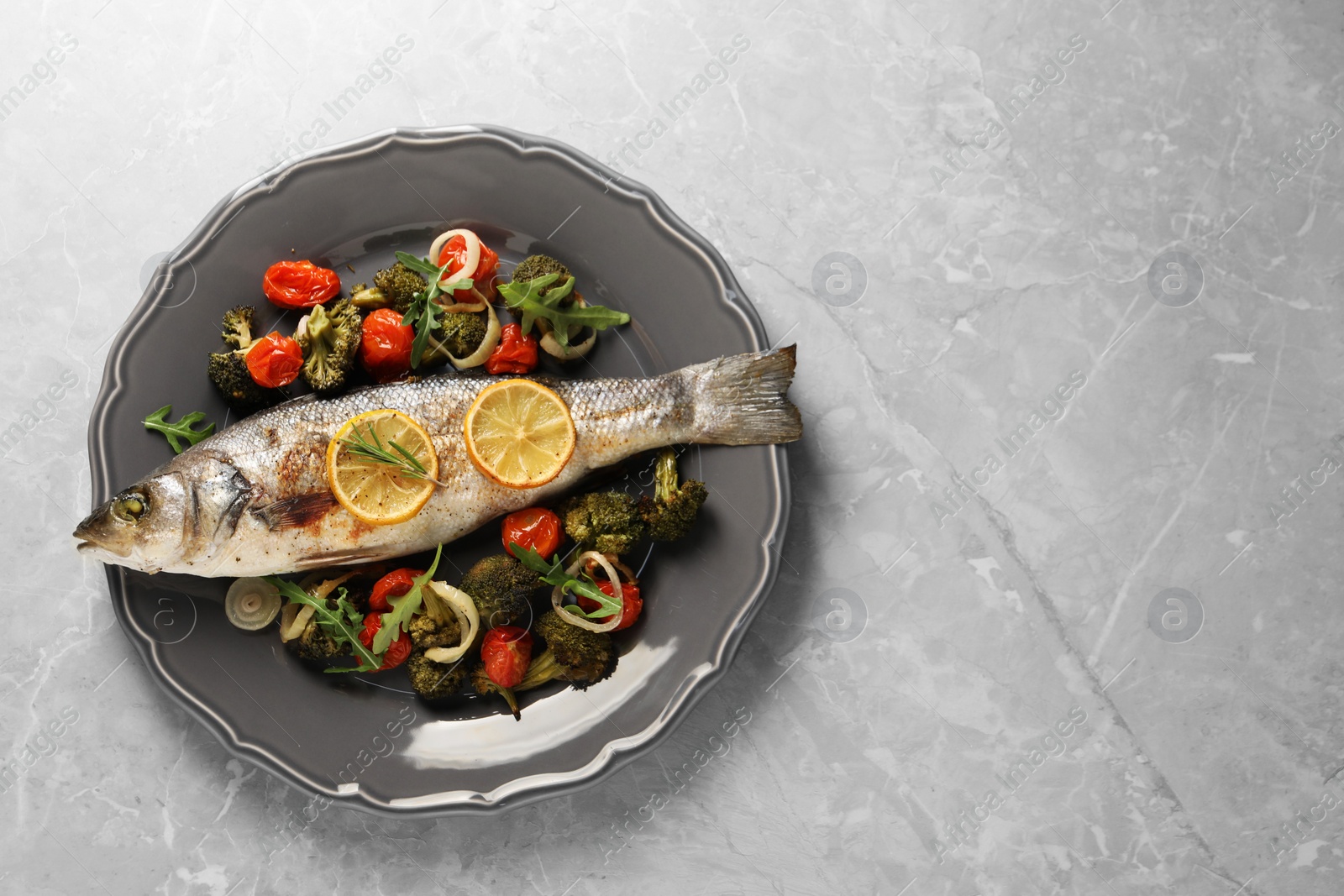 Photo of Baked fish with vegetables and lemon on grey textured table, top view. Space for text