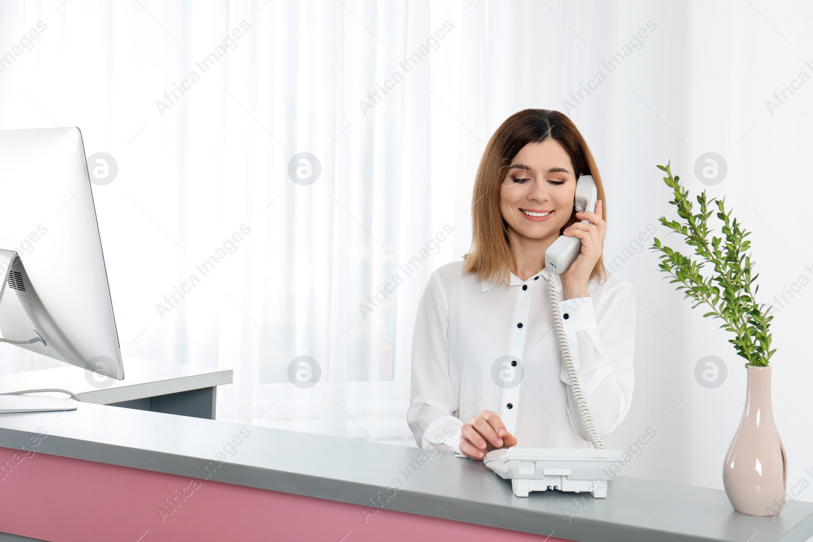 Photo of Beautiful woman talking on phone at reception desk in beauty salon