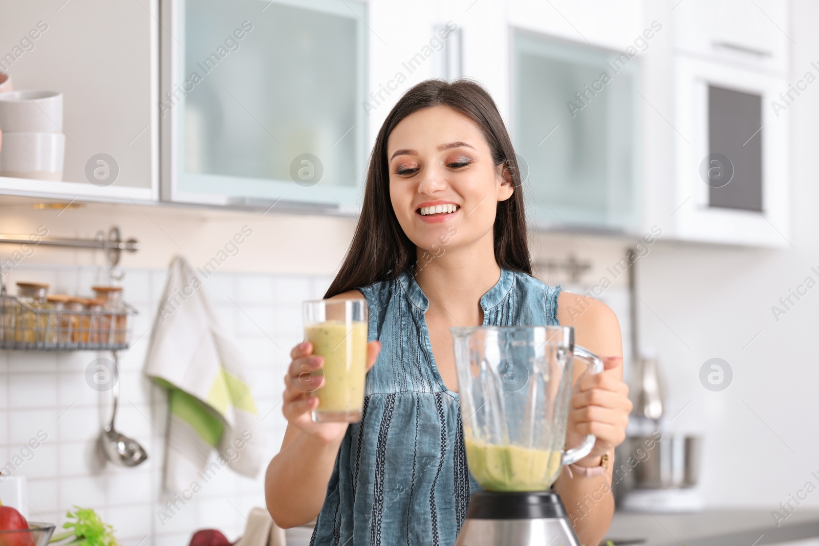 Photo of Young woman with tasty healthy smoothie in kitchen