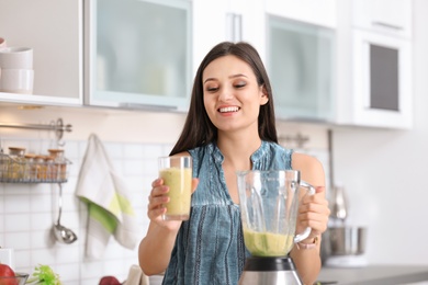 Photo of Young woman with tasty healthy smoothie in kitchen