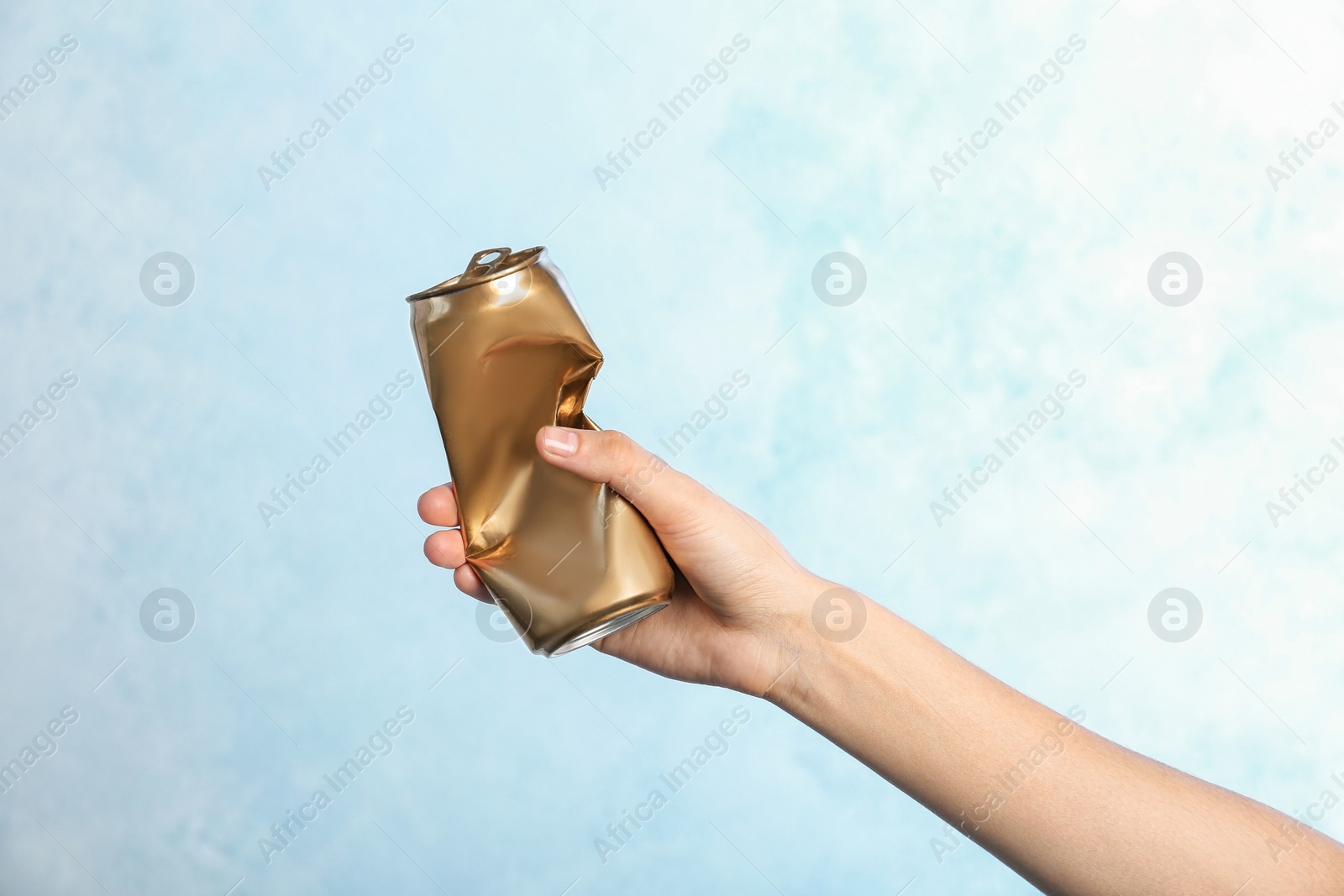 Photo of Woman holding crumpled aluminum can on color background. Metal waste recycling