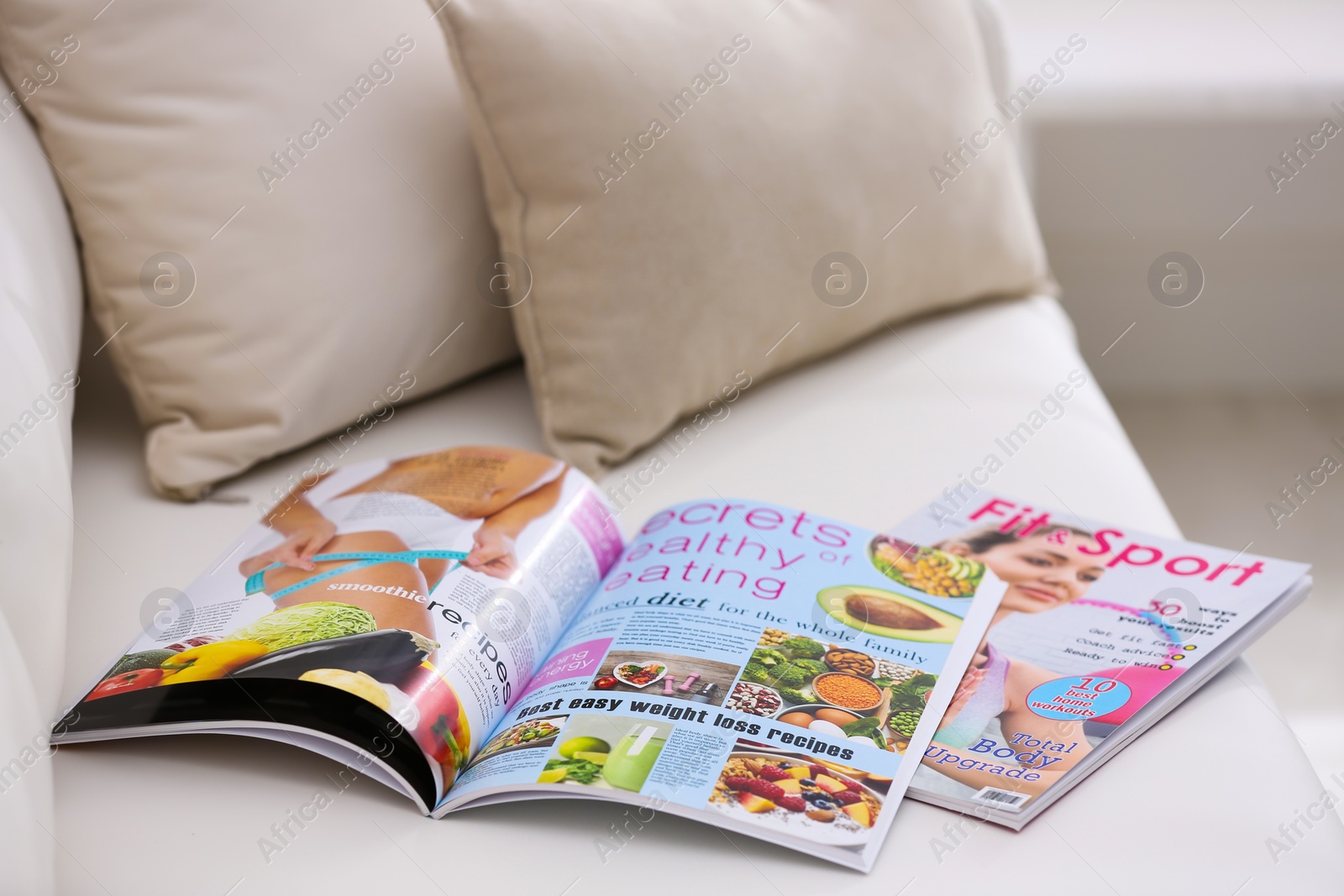 Photo of Different women's modern magazines on sofa in living room
