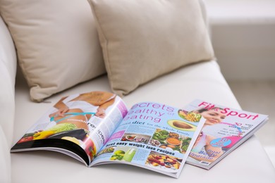 Different women's modern magazines on sofa in living room