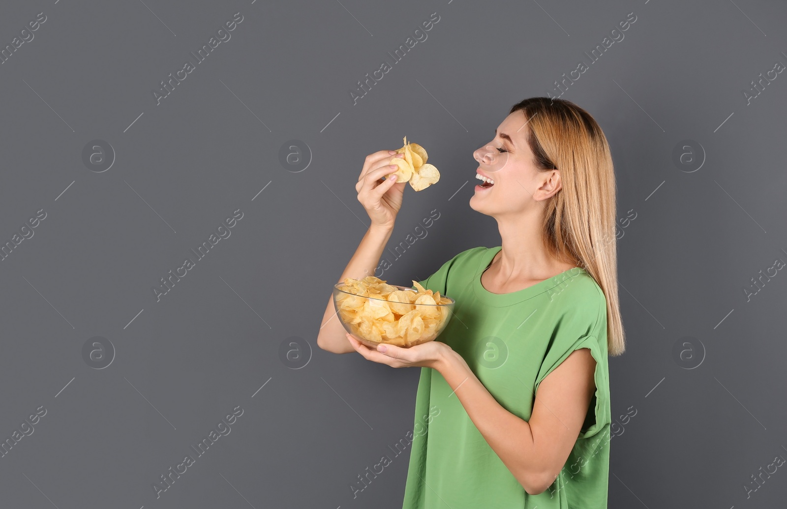 Photo of Woman eating potato chips on grey background