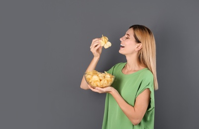 Photo of Woman eating potato chips on grey background