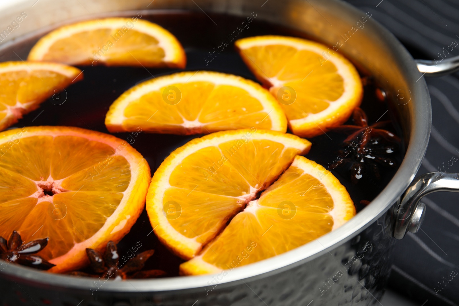 Photo of Tasty mulled wine with spices in cooking pot, closeup