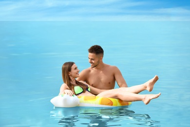 Happy woman in bikini floating on inflatable ring and her boyfriend in sea. Lovely couple