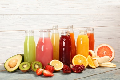 Photo of Bottles with tasty juices and ingredients on table