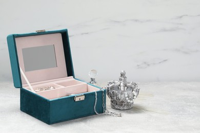 Photo of Jewelry box with many different accessories, perfume and decor on light grey table. Space for text