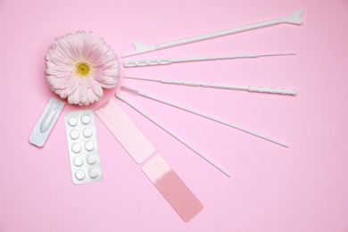 Photo of Gynecological treatment. Sterile tools, pills and gerbera flower on pink background, flat lay