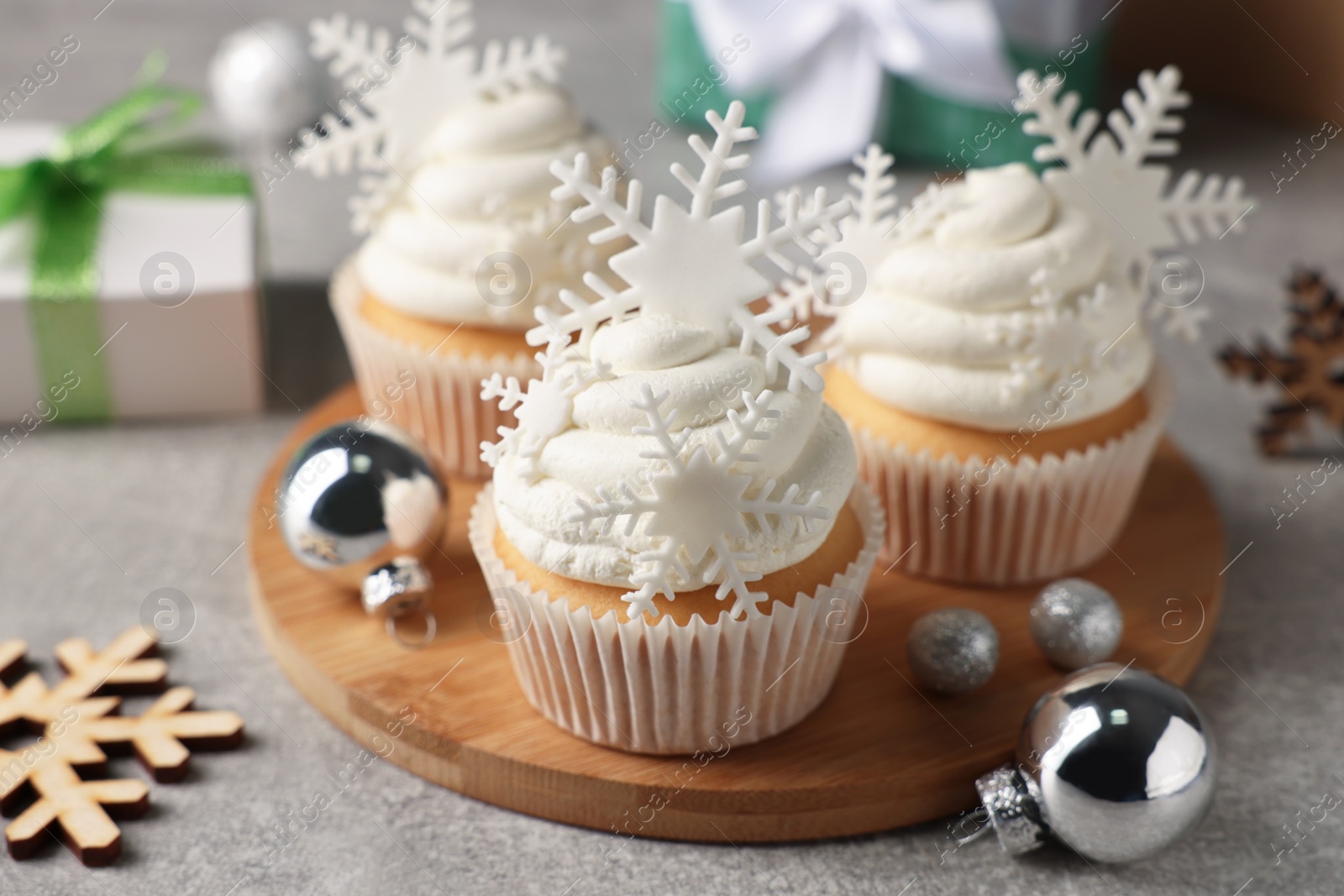 Photo of Tasty Christmas cupcakes with snowflakes and festive decor on grey table
